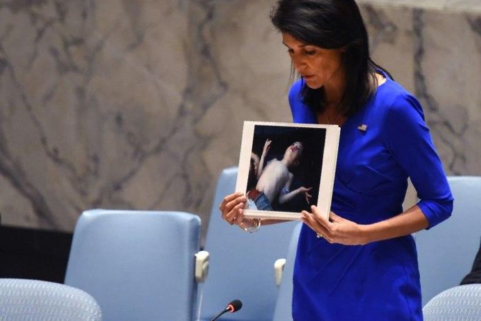 US Ambassador to the UN Nikki Haley holds photos of victims as she speaks at the UN Security Council on April 5, 2017, about the suspected deadly chemical attack that killed civilians, including children, in Syria