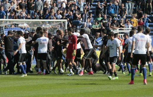 Stewards and Lyon staff members try to stop Bastia's supporters who invade the pitch to fight with Lyon players during warm up prior to the French L1 Football match between Bastia and Lyon on April 16, 2017, at the Armand Cesari stadium