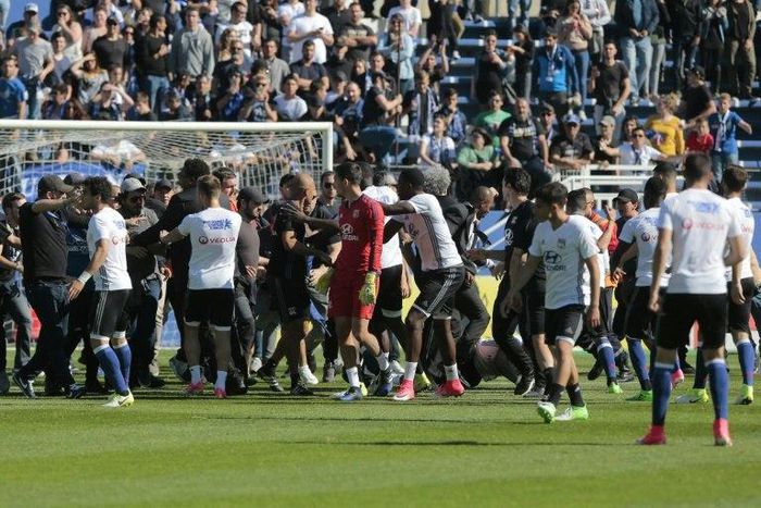 Stewards and Lyon staff members try to stop Bastia's supporters who invade the pitch to fight with Lyon players during warm up prior to the French L1 Football match between Bastia and Lyon on April 16, 2017, at the Armand Cesari stadium