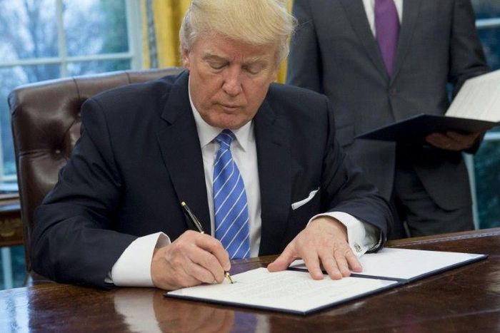 US President Donald Trump signs an executive order withdrawing the US from the Trans-Pacific Partnership in the Oval Office of the White House on January 23, 2017
