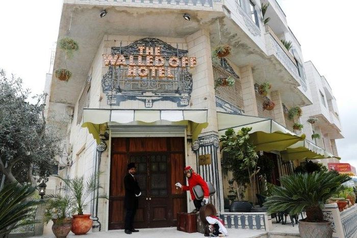 A bellboy stands outside UK street artist Banksy's newly-opened Walled Off hotel in the West Bank town of Bethlehem, on March 3, 2017