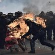 French anti-riot police try to push away a burning trolley launched towards them at a May Day rally in Paris
