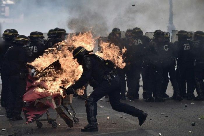 French anti-riot police try to push away a burning trolley launched towards them at a May Day rally in Paris