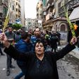 An Egyptian woman raises braided palm leaves, originally intended for Palm Sunday celebrations, during a gathering outside the Coptic Orthodox Patriarchate in Alexandria after a bomb blast struck outside while worshippers attended Palm Sunday mass on A...