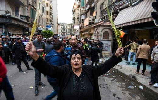 An Egyptian woman raises braided palm leaves, originally intended for Palm Sunday celebrations, during a gathering outside the Coptic Orthodox Patriarchate in Alexandria after a bomb blast struck outside while worshippers attended Palm Sunday mass on A...