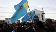 Crimean Tatars hold Ukrainian and Tatar flags at a memorial ceremony marking the 70th anniversary of the deportation of Tatars from Crimea, near a Mosque in Simferopol on May 17, 2014
