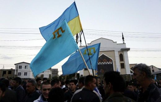 Crimean Tatars hold Ukrainian and Tatar flags at a memorial ceremony marking the 70th anniversary of the deportation of Tatars from Crimea, near a Mosque in Simferopol on May 17, 2014
