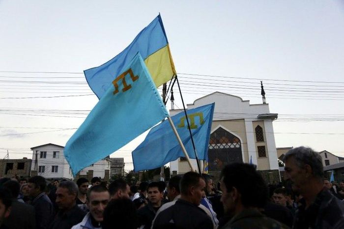 Crimean Tatars hold Ukrainian and Tatar flags at a memorial ceremony marking the 70th anniversary of the deportation of Tatars from Crimea, near a Mosque in Simferopol on May 17, 2014