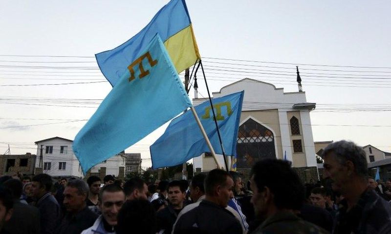 Crimean Tatars hold Ukrainian and Tatar flags at a memorial ceremony marking the 70th anniversary of the deportation of Tatars from Crimea, near a Mosque in Simferopol on May 17, 2014