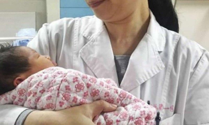 A doctor holds the healthy newborn boy at the First Affiliated Hospital of Sun Yat-sen University, in Guangdong.