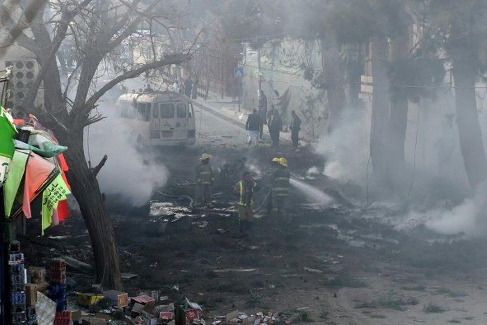 Firefighters work to extinguish a fire at the site of an explosion which struck a bus during rush hour in downtown Kabul on March 13, 2017
