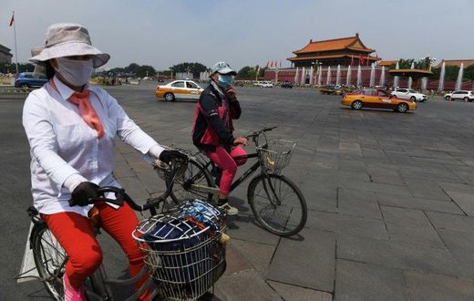 Cyclists ride past Tiananmen Gate on the eve of the 28th anniversary of the June 4, 1989 crackdown on pro-democracy protests in Beijing