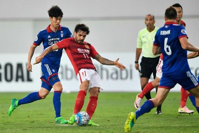 Ricardo Goulart (in red) of Guangzhou Evergrande shoots against Suwon Samsung Bluewings during their AFC Champions League match in Guangzhou, on May 9, 2017