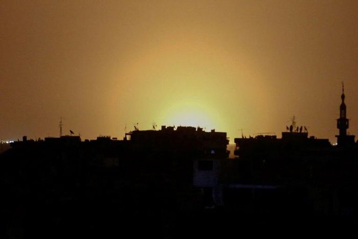 A photo taken from the rebel-held town of Douma shows flames rising in the distance which are believed to be coming from Damascus International Airport following an explosion early in the morning of April 27, 2017