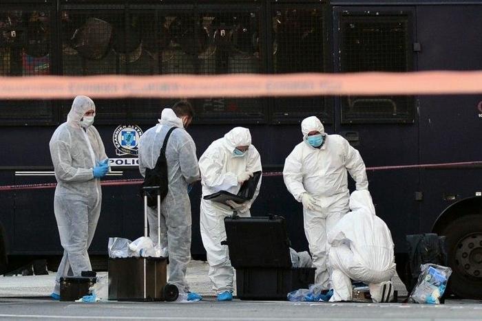 Police officers examine the entrance to the French embassy in central Athens, after two motorcyclists threw a hand granade and injured the guard, early on November 10, 2016
