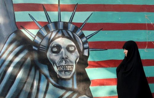 An Iranian woman walks past a mural on the wall of the former US embassy in Tehran