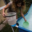 Woman draws water from a pool during a drinking water supply cut in Santiago, on February 26, 2017 where more than 1.4 million homes have been affected by a water cut from heavy rains in three regions of central Chile