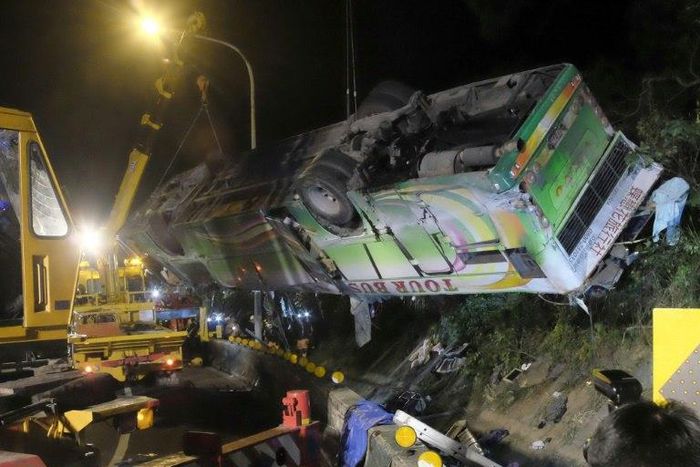 A bus that crashed along a highway is lifted by cranes in Taipei on February 14, 2017