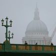 Pedestrians walk through the fog as they cross Southwark Bridge in London as St Paul's Cathedral looms in the background on January 23, 2017
