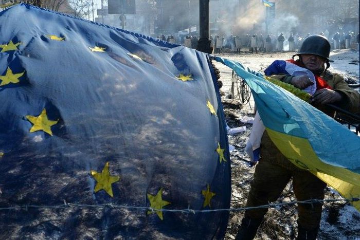 An anti-government opposition activist places European Union and Ukrainian flags side by side at a barricade in Kiev on February 2, 2014