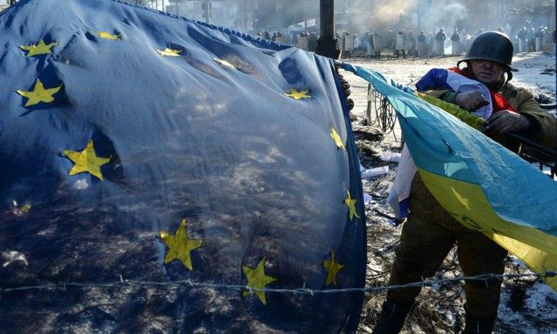 An anti-government opposition activist places European Union and Ukrainian flags side by side at a barricade in Kiev on February 2, 2014