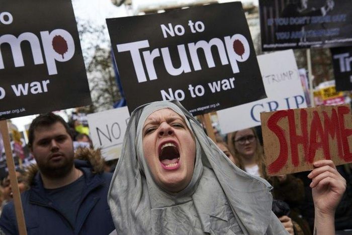 Demonstrators hold placards in protest against US President Donald Trump outside US Embassy in London on February 4, 2017