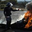 A policeman tries to extinguish a fire after demonstrators burnt tyres to barricade a road during violent protests in Ennerdale