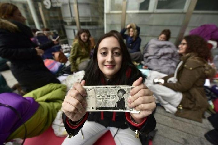 A fan of Canadian popstar Justin Bieber poses with her ticket outside the concert hall in Madrid, on November 18, 2016