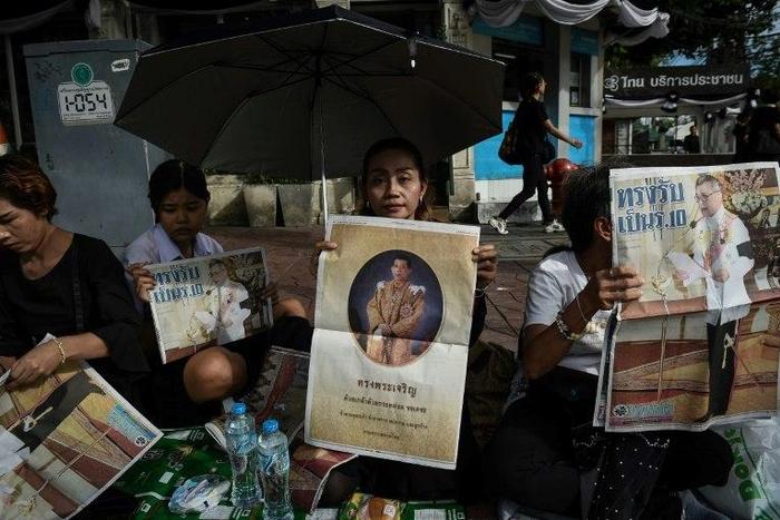 People hold newspaper images of Thailand's new King Maha Vajiralongkorn outside the Grand Palace in Bangkok