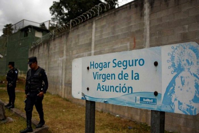 Police agents stand guard next to a sign that reads "Sage home Virgen de la Asuncion" at the children's shelter entrance after 40 girls died during a fire on March 8, in San Jose Pinula, on March 15, 2017