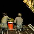 US Coast Guard officers sit on the ramp of an HC-130 Hercules and prepare to deploy a long range drop kit to a disabled vessel approximately 80 miles off Tonga