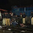 Pakistani policemen and volunteers move the bodies of victims at the site of a bomb explosion in Lahore on February 13, 2017