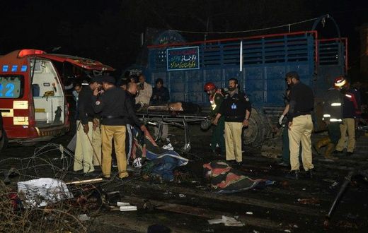 Pakistani policemen and volunteers move the bodies of victims at the site of a bomb explosion in Lahore on February 13, 2017