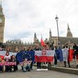 Demonstrators with national flags including that of Poland (centre) pose in front of "Big Ben" in London during a "Flag Mob" rally on February 20, 2017 in support of migrants in the UK