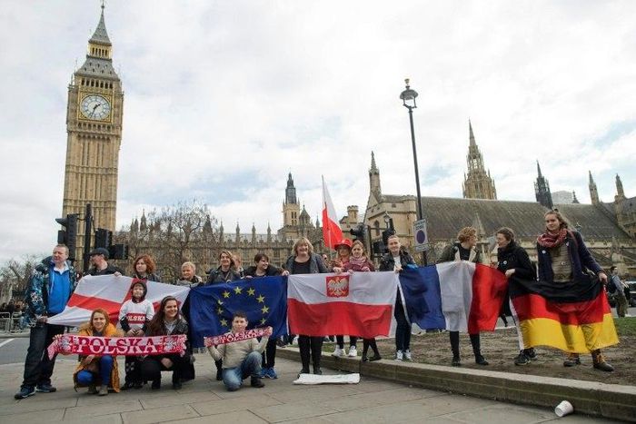 Demonstrators with national flags including that of Poland (centre) pose in front of "Big Ben" in London during a "Flag Mob" rally on February 20, 2017 in support of migrants in the UK