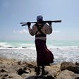 An armed Somali pirate walks along the coastline near Hobyo in 2010