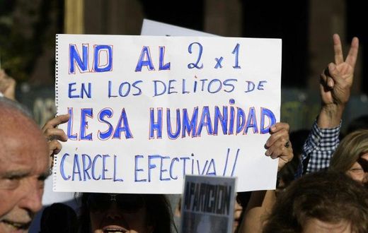 A demonstrator holds a sign reading in Spanish "No two for one for crimes against humanity; full jail-time!" during the Madres de Plaza de Mayo human rights group's weekly demonstration at the Plaza de Mayo square in Buenos Aires on May 4, 2017