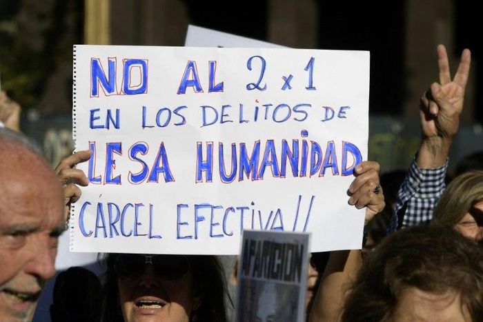 A demonstrator holds a sign reading in Spanish "No two for one for crimes against humanity; full jail-time!" during the Madres de Plaza de Mayo human rights group's weekly demonstration at the Plaza de Mayo square in Buenos Aires on May 4, 2017