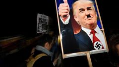 A demonstrator holds a placard showing a picture of US President-elect Donald Trump modified to add a swastika and an Adolf Hitler-style moustache during a protest outside the US Embassy in London