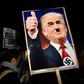 A demonstrator holds a placard showing a picture of US President-elect Donald Trump modified to add a swastika and an Adolf Hitler-style moustache during a protest outside the US Embassy in London