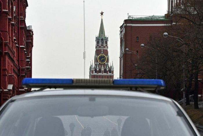 A group of men pictured through a police car window in central Moscow, with the Kremlin's Spasskaya (Saviour) Tower seen in the background, on March 1, 2017