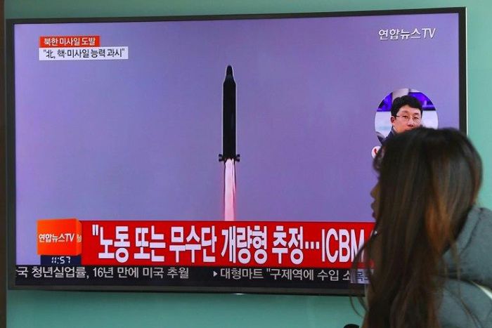 A woman walks past a television screen showing file footage of North Korea's missile launch at a railway station in Seoul on February 12, 2017