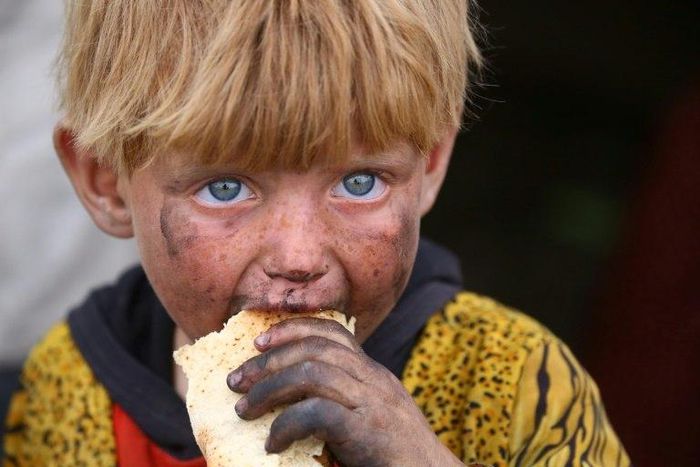 A displaced Syrian child eats at a temporary camp in the village of Ain Issa on May 1, 2017. People have been arriving at the camp for months, but the pace has picked up as the Syrian Democratic Forces militia presses its offensive against IS