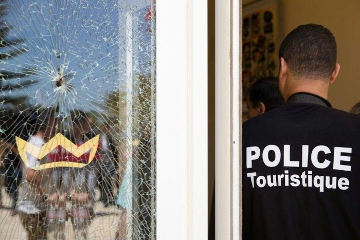 A Tunisian police officer stands guard near a bullet hole at the the Riu Imperial Marhaba Hotel after an attack that left 38 people dead on June 25, 2015