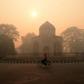 A cyclist rides along a street as smog envelops a monument in New Delhi on October 31, 2016, a day after the Diwali festival