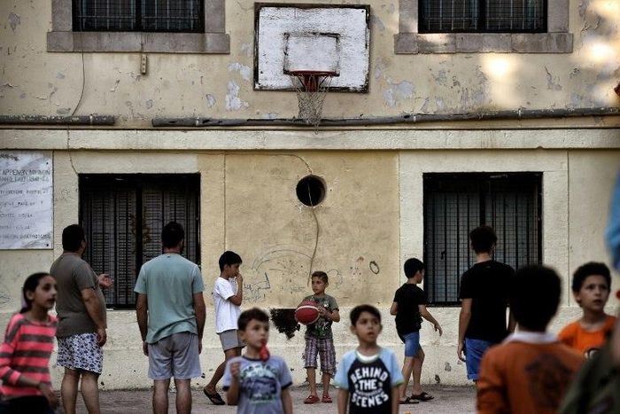 Children play in the courtyard of an abandoned school used to host Syrian and Afghan refugees in Athens on July 1, 2016