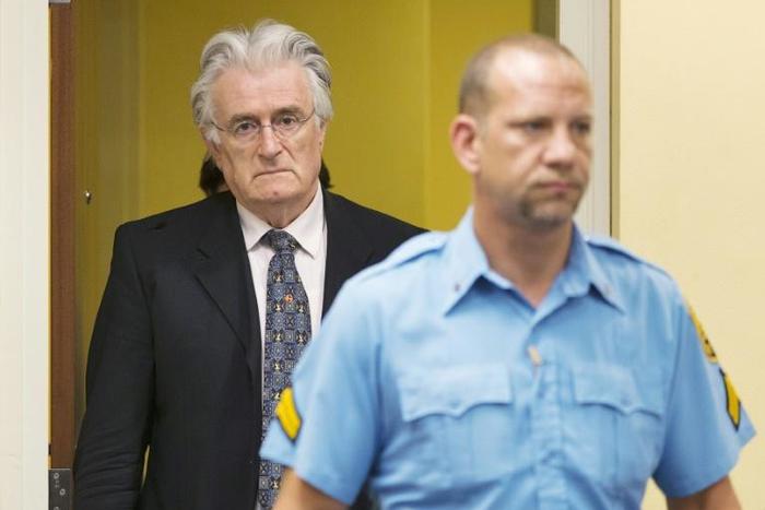 Bosnian Serb wartime leader Radovan Karadzic (left) is led into the courthouse during a 2013 appearance at the International Criminal Tribunal for Former Yugoslavia (ICTY) in The Hague