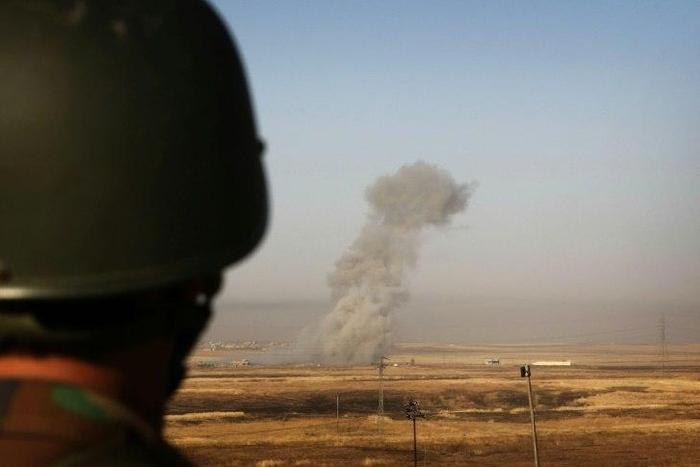 Smoke billows on the front line as an Iraqi Kurdish peshmerga fighter looks on from a position east of the city of Mosul