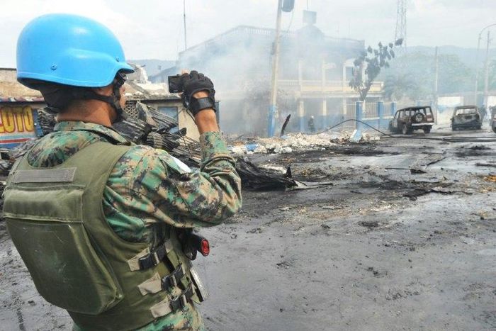 A UN peacekeeper inspects the aftermath of a 2013 blaze that swept through a market in Port-au-Prince