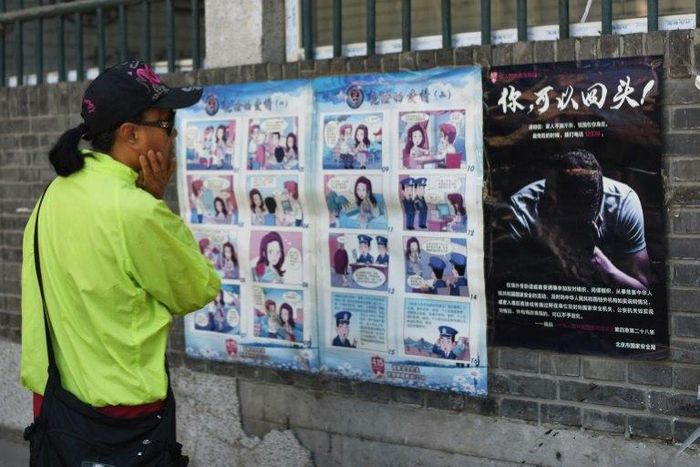 A woman looks at a propaganda cartoon warning local residents about foreign spies, in an alley in Beijing on May 23, 2017